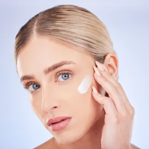 Skincare, face portrait and woman with cream in studio isolated on a blue background. Dermatology c