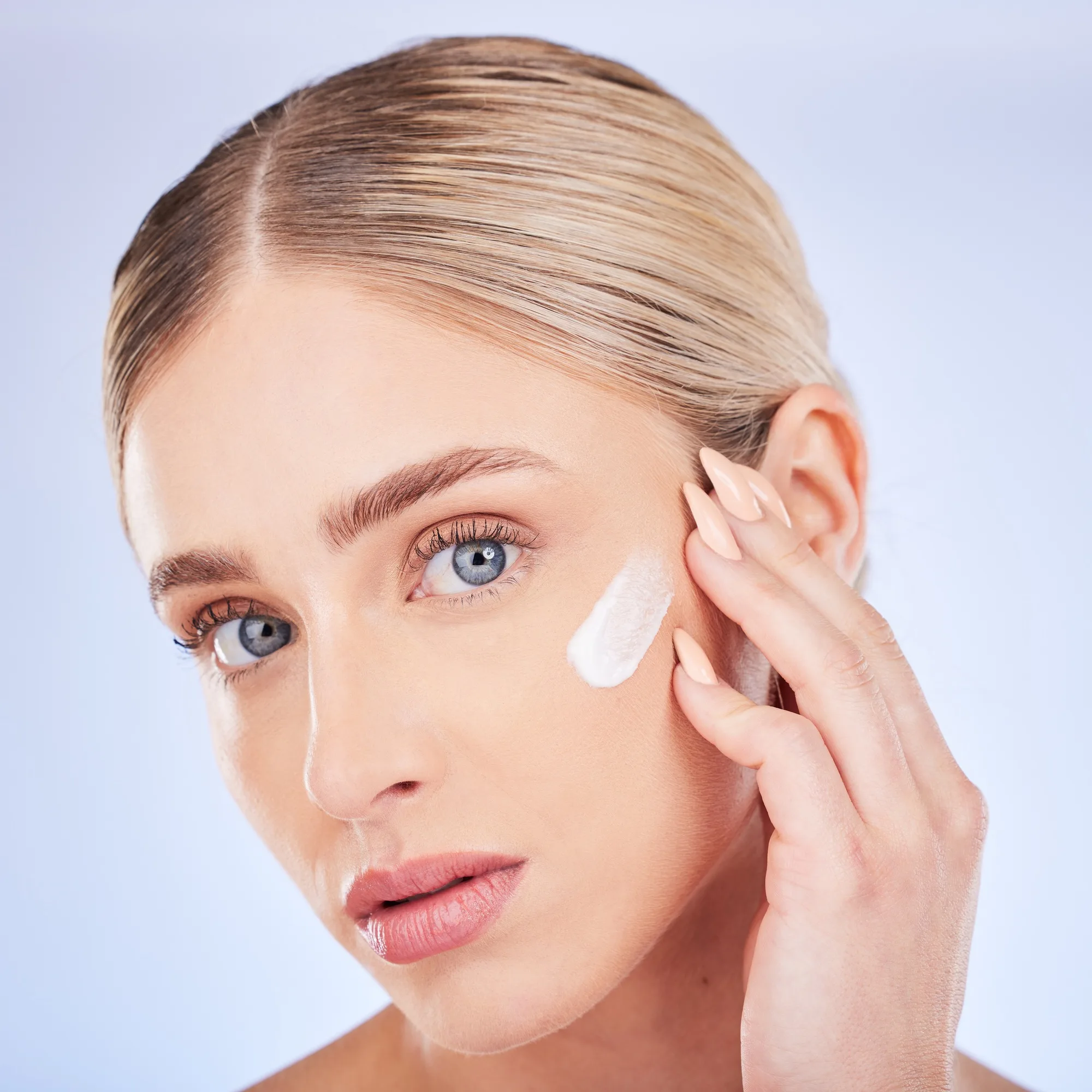 Skincare, face portrait and woman with cream in studio isolated on a blue background. Dermatology c